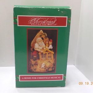 May include: A green box with a red rectangular label that reads "Christmas Around The World". The box features a detailed image of Santa Claus and an elf. The text "A Home For Christmas Musical" is at the bottom.
