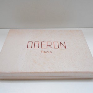 May include: A white box with the words "OBÉRON Paris" printed in red on the top.