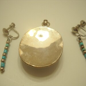 Op de afbeelding: Een zilveren hanger met een turquoise steen en een bijpassend paar oorclips met turquoise kralen.