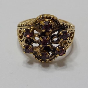 May include: A gold ring with a filigree design and purple gemstones.