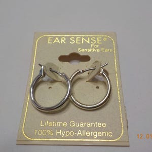 May include: A pair of silver hoop earrings on a card that reads "Ear Sense For Sensitive Ears" and "Lifetime Guarantee 100% Hypo-Allergenic".