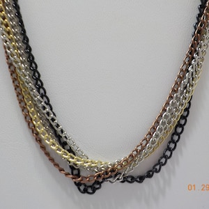 May include: A multi-strand necklace with four chains in black, silver, gold, and copper.