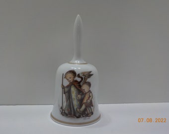 May include: White porcelain bell with a gold trim. The bell features a painted image of two angels, one with wings, holding hands. The image is in a vintage style.
