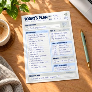 Può includere: Un foglio di pianificazione giornaliera bianco intitolato Today's Plan con testo blu e sezioni per One Priority, Brain Dump, Top 3, Time/Appointments, Energy, Must Remember e Today's Win. La pagina include attività scritte a mano e la data 9/15/25.