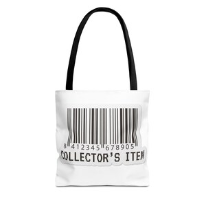 Op de afbeelding: Een witte tote bag met zwarte hengsels voorzien van een grote zwarte barcode-afbeelding op de voorzijde. Onder de barcode staat de tekst COLLECTOR'S ITEM gedrukt in een vet, gepixeld zwart lettertype. Het ontwerp is gecentreerd op de tas.