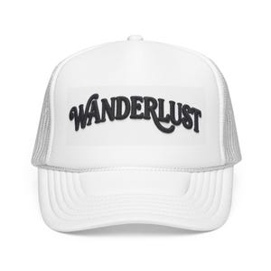 May include: A white trucker hat featuring a mesh back and a solid front panel. The word WANDERLUST is embroidered in black, bold, cursive lettering across the center of the front panel. The hat includes a curved brim and a structured crown.