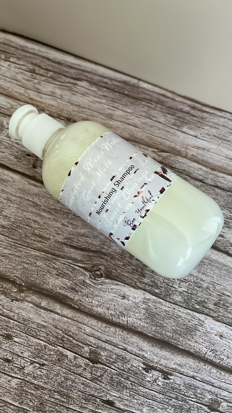 Puede incluir: Una botella de champ&uacute; blanca y transparente con tap&oacute;n blanco. La etiqueta dice "Fermented Rice Water, Goat Milk, Nourishing Shampoo, Sweet Orange, Bee Youthful!". La botella contiene un l&iacute;quido verde claro.