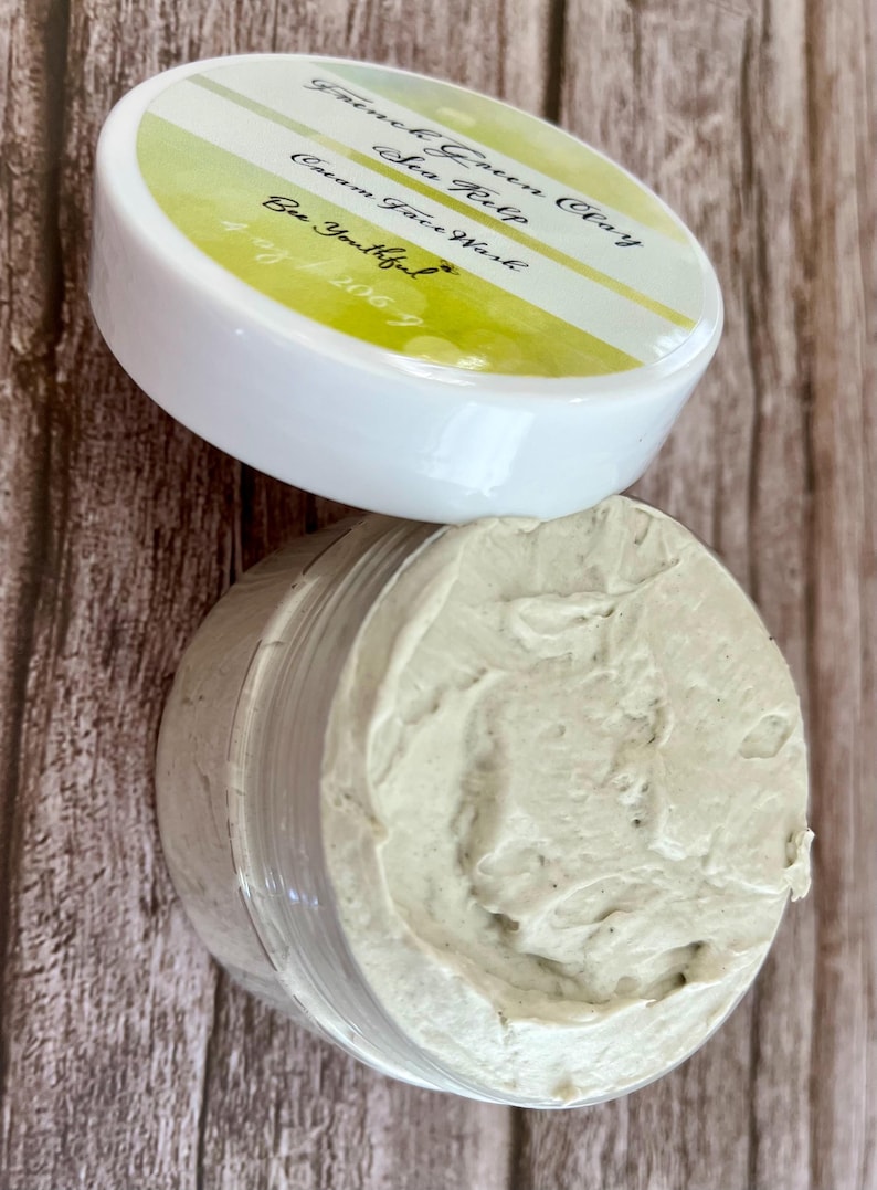 May include: A white jar with a green and yellow label that reads "French Green Clay Sea Kelp Cream Face Wash Be Youthful #201067". The jar is filled with a light green face mask.