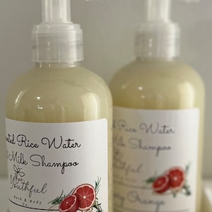 Puede incluir: Dos botellas de champ&uacute; transparentes con etiquetas blancas. Las etiquetas dicen "Fermented Rice Water & Milk Shampoo" y "Rosemary Orange". Cada etiqueta presenta un gr&aacute;fico de una naranja en rodajas y ramitas de romero. Las botellas tienen dispensadores de bomba blancos.