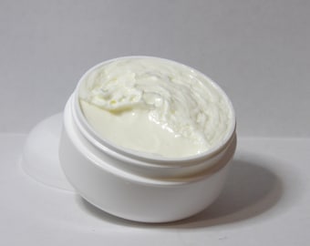 May include: A white plastic jar with a white lid, partially filled with a white creamy substance. The lid is off and the cream is overflowing.