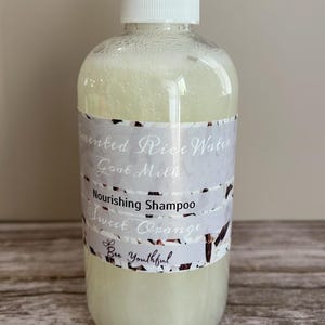 Puede incluir: Una botella de pl&aacute;stico transparente de champ&uacute; con una tapa de bomba blanca. La etiqueta dice "Fermented Rice Water Goat Milk Nourishing Shampoo Sweet Orange" y "Bee Youthful". El champ&uacute; es de color amarillo p&aacute;lido.