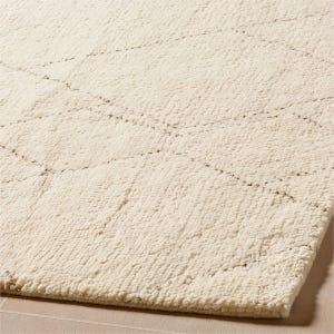 Puede incluir: Una alfombra de color crema con una superficie de pelo grueso y texturizado. La alfombra presenta un sutil patrón geométrico de diamantes repetitivos formado por finas líneas de color marrón oscuro tejidas en la tela por toda la superficie.
