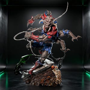 Op de afbeelding: Een meerarmig wezenfiguur met een getextureerd bruin lichaam, scherpe tanden en een rood-blauw pak met gerafelde randen. Het figuur staat op een gedetailleerde basis met een bakstenen muur, een groene staart en doorschijnende barnsteenkleurige elementen.