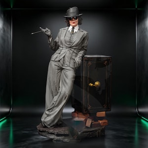 Könnte beinhalten: Eine graue Figur, die einen Fedora, eine Sonnenbrille, ein Hemd mit Kragen, eine Krawatte und einen Anzug trägt und sich an einen schwarzen Tresor mit goldenen Akzenten lehnt. Die Figur hält einen dünnen Stab und steht auf einem Sockel aus Stein und Ziegeln.