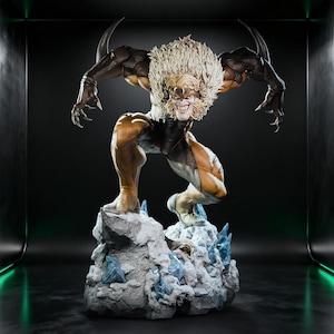 May include: A detailed collectible statue of a muscular humanoid figure with a large mane of blonde hair, sharp claws, and a snarling expression. The figure wears a brown and tan bodysuit and stands atop a textured, rocky base with blue ice shards.