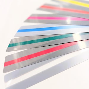 May include: A fan-shaped arrangement of rectangular silver strips, each featuring a single horizontal stripe in a different colour including yellow, coral, hot pink, light blue, teal, and red, with one plain silver strip at the bottom.