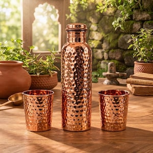 May include: A tall, cylindrical copper water bottle with a hammered texture and a matching screw-top lid, flanked by two smaller, matching hammered copper tumblers. The set features a polished, reflective metallic finish throughout the exterior.