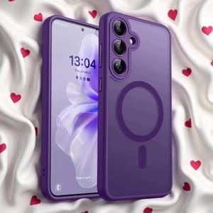Può includere: Una custodia per smartphone viola con un anello magnetico circolare sul retro, mostrata accanto a uno smartphone che visualizza l'ora 13:04 e la data giovedì 2 gennaio. La custodia presenta tre ritagli per l'obiettivo della fotocamera.