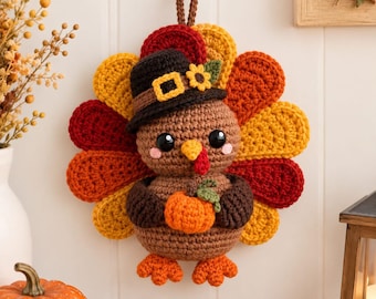 Könnte beinhalten: Ein gehäkelter Truthahn-Wandschmuck mit braunem Körper, einem Fächer aus gelben, orangefarbenen und roten Federn sowie einem schwarzen Hut mit gelber Schnalle und Sonnenblume. Der Truthahn hält einen kleinen orangefarbenen Kürbis und hat orange Füße.