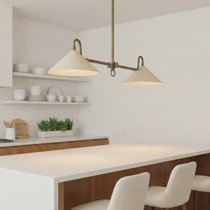 Puede incluir: Una lámpara colgante lineal con dos pantallas cónicas de color blanco roto suspendidas de una varilla central de metal en tono latón. La lámpara presenta un diseño de barra horizontal con brazos curvos que conectan las pantallas al soporte.