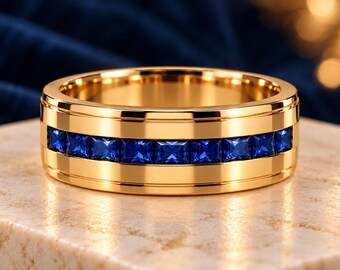 May include: A polished gold band ring featuring a central channel set with a row of square-cut blue gemstones. The ring has a smooth, reflective metallic finish and a flat profile, showcasing a continuous line of vibrant blue stones.