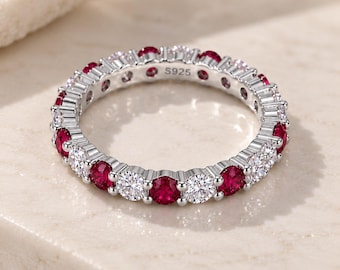 Peut inclure: Une bague éternité en argent sterling ornée d'un motif alterné de pierres rondes rouges et de pierres blanches transparentes. L'intérieur de l'anneau porte l'inscription S925, indiquant la composition métallique de ce bijou circulaire.