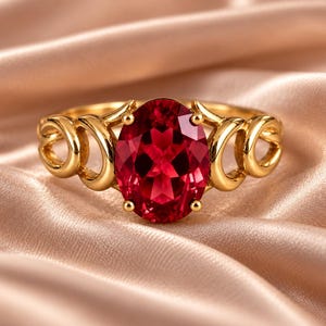 Può includere: Un anello in oro con una grande pietra preziosa rosso intenso dal taglio ovale, fissata da quattro griffe. La fascia è realizzata in oro giallo lucido e presenta un intricato design traforato con anelli circolari su entrambi i lati.