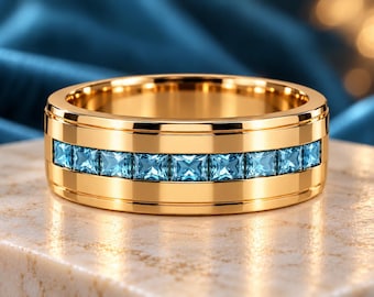 May include: A polished gold band ring featuring a central channel set with a row of square-cut light blue gemstones. The ring has a smooth, reflective finish and a wide profile, showcasing a continuous line of blue stones around the center.