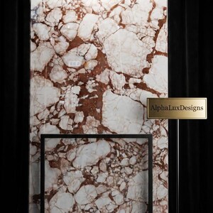 Pode incluir: Uma grande placa retangular de mármore brechado branco e castanho-avermelhado com acabamento polido, exibida numa moldura de metal preto. Uma placa retangular dourada num suporte preto fino apresenta o texto AlphaLuxDesigns em preto.