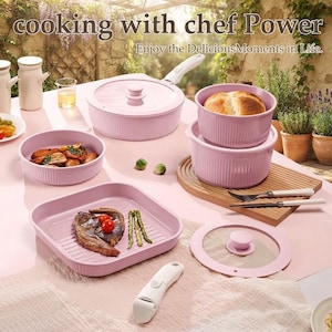 May include: A set of pastel pink cookware including a lidded pan, a square grill pan, and two round bowls. The set features a detachable white handle, a glass lid, and ribbed exterior textures. Text reads: cooking with chef Power Enjoy the DeliciousMoments in Life.