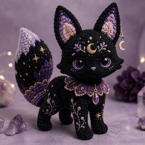 Könnte beinhalten: Ein schwarzer gehäkelter Fuchs mit violetten Akzenten, verziert mit gestickten goldenen Sternen und floralen Mustern. Er hat große violette Augen, eine Mondsichel auf der Stirn, einen Rüschenkragen mit violettem Kristallanhänger und einen Mondanhänger.