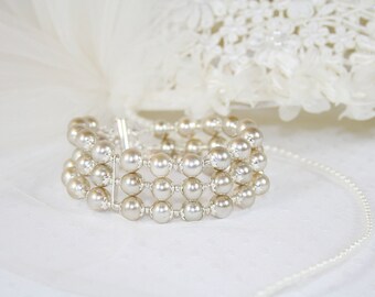 May include: A white pearl bracelet with three rows of pearls. The bracelet is made of small, round pearls that are strung together on a silver wire.