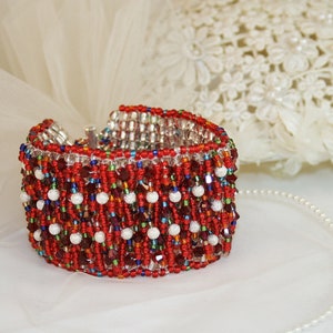 May include: A red, white, and blue beaded bracelet with a silver clasp. The bracelet is made of small, round beads and has a fringe-like design.