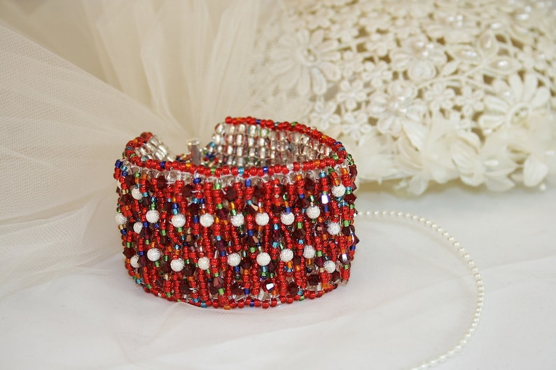 May include: A red, white, and blue beaded bracelet with a silver clasp. The bracelet is made of small, round beads and has a fringe-like design.