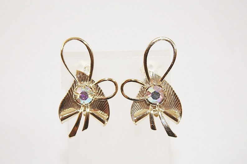 May include: A pair of gold-tone clip-on earrings with a bow design and iridescent rhinestones.