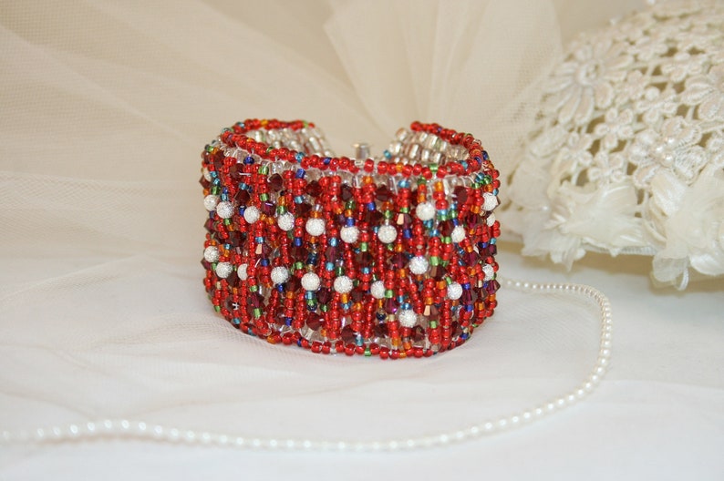 May include: A red, white, and blue beaded bracelet with a silver clasp. The bracelet is made with small, round beads and has a sparkly finish.
