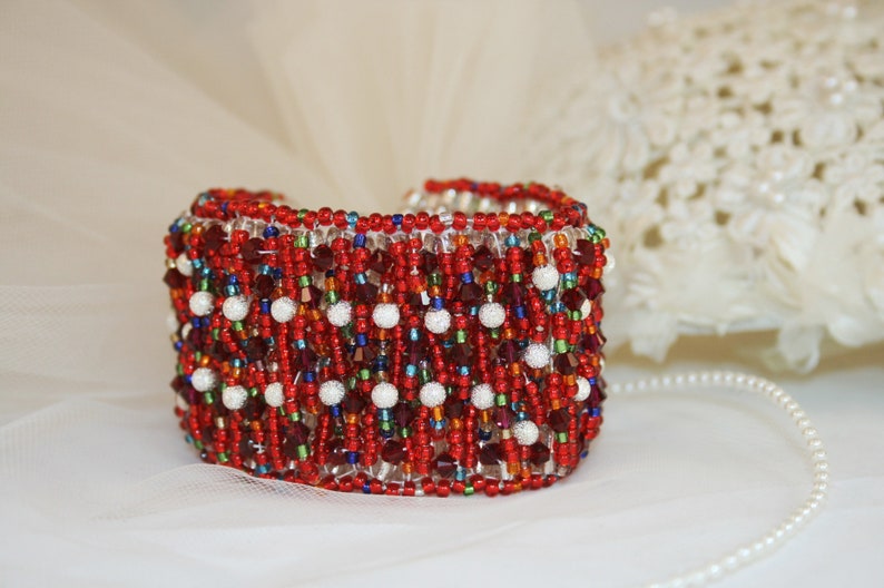 May include: A red, white, and blue beaded bracelet with a geometric pattern. The bracelet is made with small glass beads and has a shiny finish.