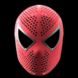 May include: A red full-face mask featuring a dense pattern of small circular perforations across the entire surface. The mask includes two large, angular eye openings outlined with a smooth, silver-coloured border, creating a distinct contrast.