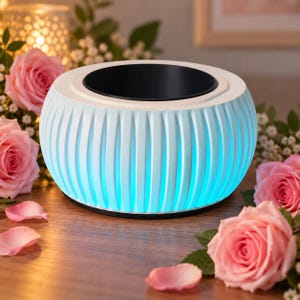 Peut inclure: Un diffuseur rond, blanc et nervuré avec une ouverture circulaire noire sur le dessus. La base du diffuseur émet une lumière bleue vive et éclatante. La surface extérieure présente des stries verticales sur toute la circonférence.
