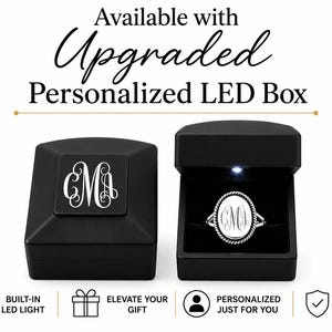 Puede incluir: Una caja de anillo negra con un monograma personalizado en la tapa y una caja abierta que contiene un anillo ovalado plateado con un monograma a juego. El texto dice Available with Upgraded Personalized LED Box, Built-in LED Light, Elevate Your Gift, Personalized Just For You y Premium Quality.