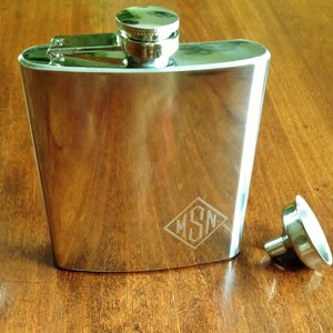 May include: A silver flask with a diamond-shaped engraving that says "MSN" and a silver funnel.