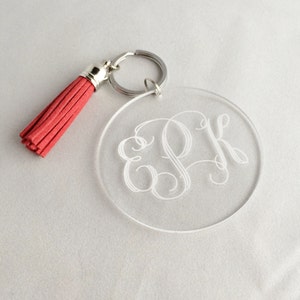 May include: A clear acrylic keychain with a silver key ring and a red tassel. The keychain has the initials "EPK" engraved in a cursive font.
