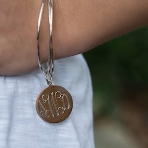 May include: A silver bangle bracelet with a silver charm that has the initials "N.L.D." engraved on it.