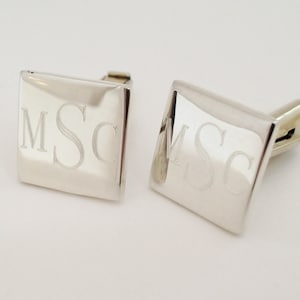 May include: A pair of silver square cufflinks with the initials "MSC" engraved on each.