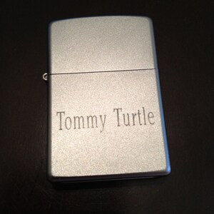 May include: A silver lighter with the name "Tommy Turtle" engraved on the front.
