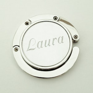 May include: Silver-toned metal purse hook with the name "Laura" engraved on the front.