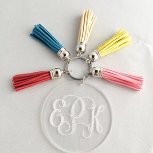Pode incluir: Um chaveiro de acr&iacute;lico transparente com um design de monograma "EPK". O chaveiro tem cinco borlas coloridas: amarelo, creme, rosa claro, vermelho e azul.