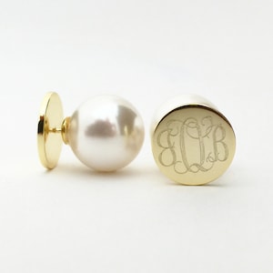 May include: A pair of gold earrings with a pearl on one side and a monogram on the other. The monogram is "E.Q.B."