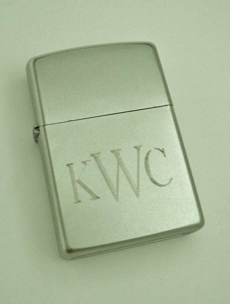 May include: A silver lighter with the initials "KWC" engraved on the front.