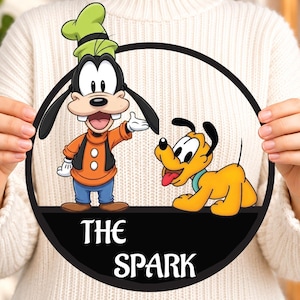 Pode incluir: Uma placa circular com uma ilustração colorida do Pateta e do Pluto. O Pateta veste um suéter laranja, colete preto e calças azuis. O Pluto é amarelo com uma coleira azul-petróleo. A parte inferior é preta com o texto branco THE SPARK.